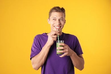 Photo of Man drinking juice through straw on orange background
