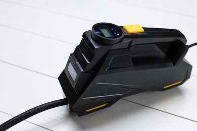 Photo of One black tire inflator on light wooden table, closeup