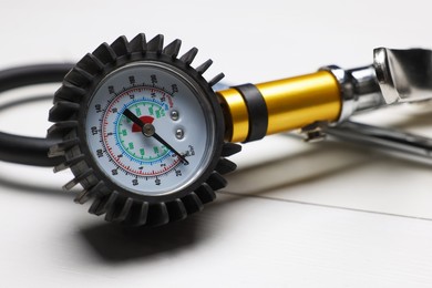 Photo of One tire inflation gun with gauge on light wooden table, closeup