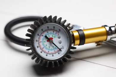 Photo of One tire inflation gun with gauge on light wooden table, closeup