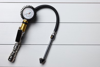 Photo of One tire inflation gun with gauge on light grey wooden table, top view