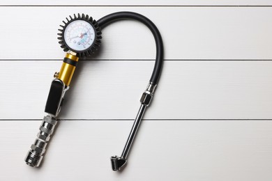 Photo of One tire inflation gun with gauge on light grey wooden table, top view