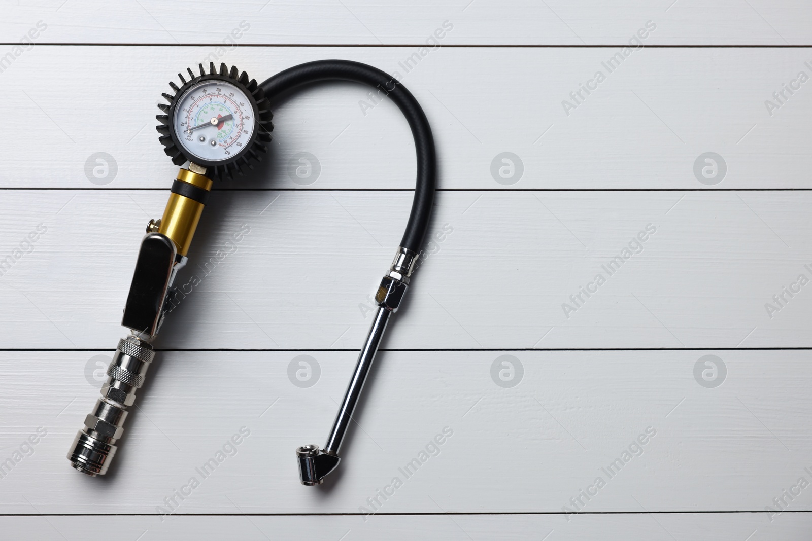 One tire inflation gun with gauge on light grey wooden table, top view. Space for text Photo of One tire inflation gun with gauge on light grey wooden table, top view. Space for text