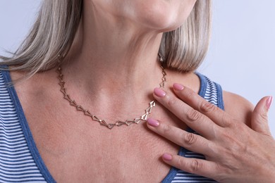 Photo of Woman wearing stylish necklace on light background, closeup