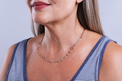 Photo of Woman wearing stylish necklace on light background, closeup