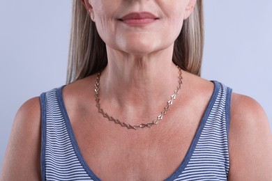 Photo of Woman wearing stylish necklace on light background, closeup