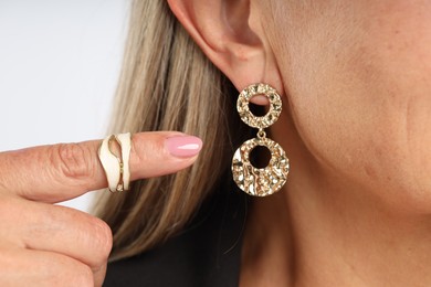 Photo of Woman wearing stylish earring and ring on light background, closeup