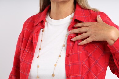 Photo of Woman wearing stylish necklace on light background, closeup