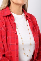 Photo of Woman wearing stylish necklace on light background, closeup