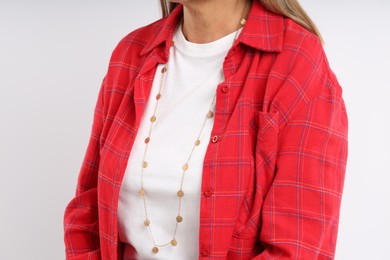 Photo of Woman wearing stylish necklace on light background, closeup