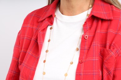 Photo of Woman wearing stylish necklace on light background, closeup