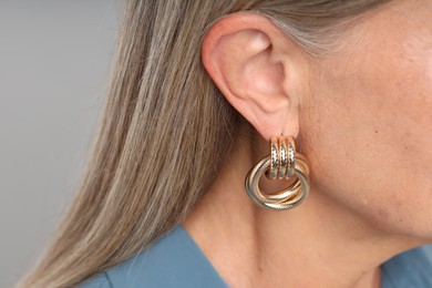 Photo of Woman wearing stylish earring on light background, closeup