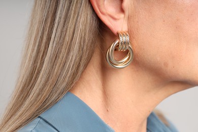 Photo of Woman wearing stylish earring on light background, closeup