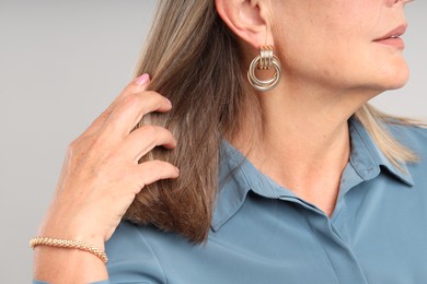 Photo of Woman wearing stylish earring and bracelet on light background, closeup