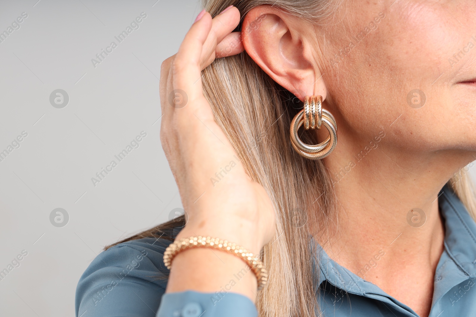 Woman wearing stylish earring and bracelet on light background, closeup Photo of Woman wearing stylish earring and bracelet on light background, closeup