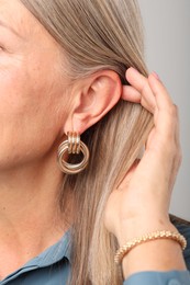 Photo of Woman wearing stylish earring and bracelet on light background, closeup