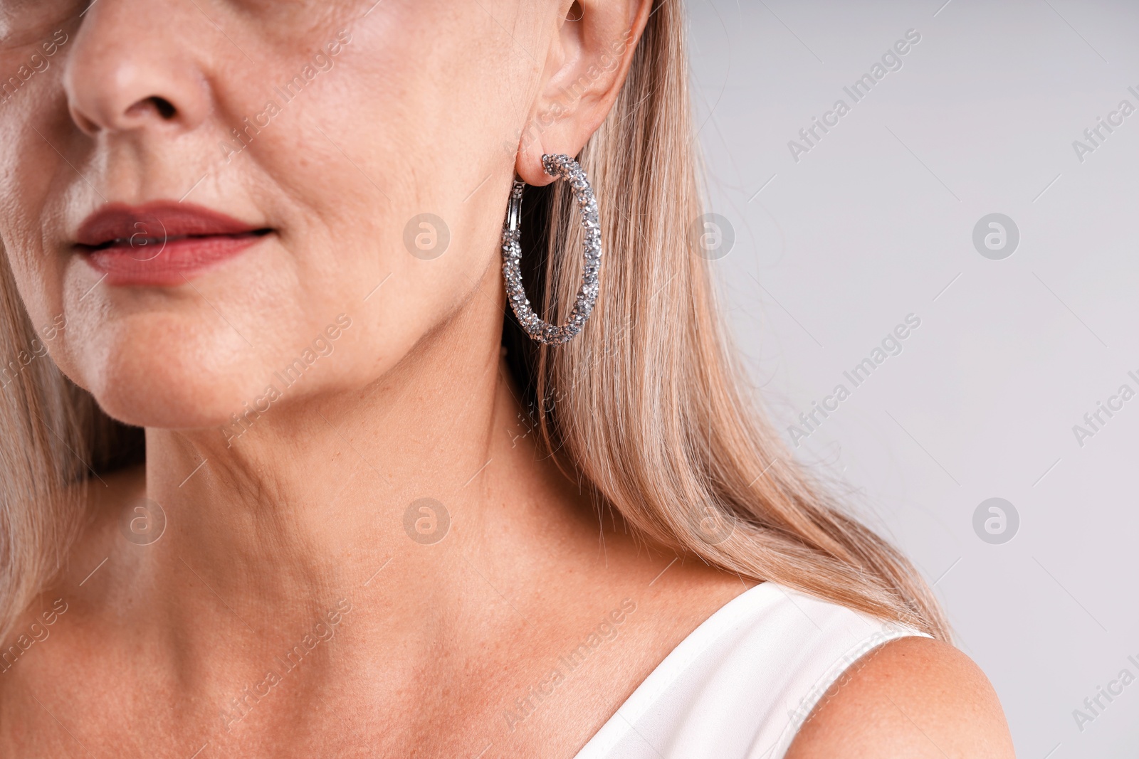 Woman wearing stylish earring on light background, closeup Photo of Woman wearing stylish earring on light background, closeup