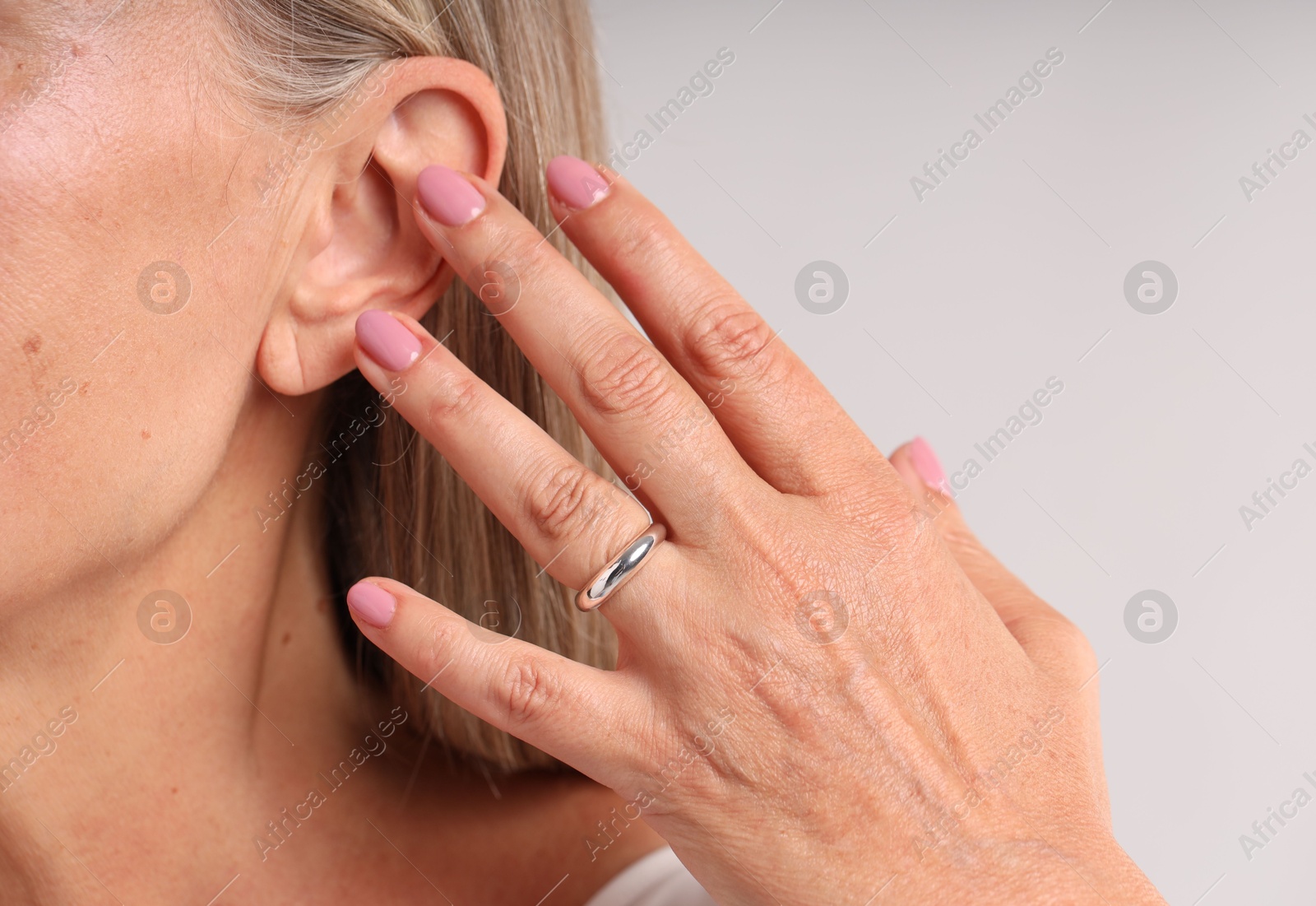 Woman wearing stylish ring on light background, closeup Photo of Woman wearing stylish ring on light background, closeup