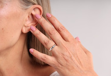 Photo of Woman wearing stylish ring on light background, closeup