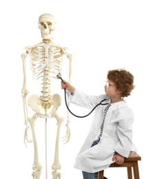 Photo of Choice of profession. Little boy with stethoscope and human skeleton model pretending to be doctor on white background