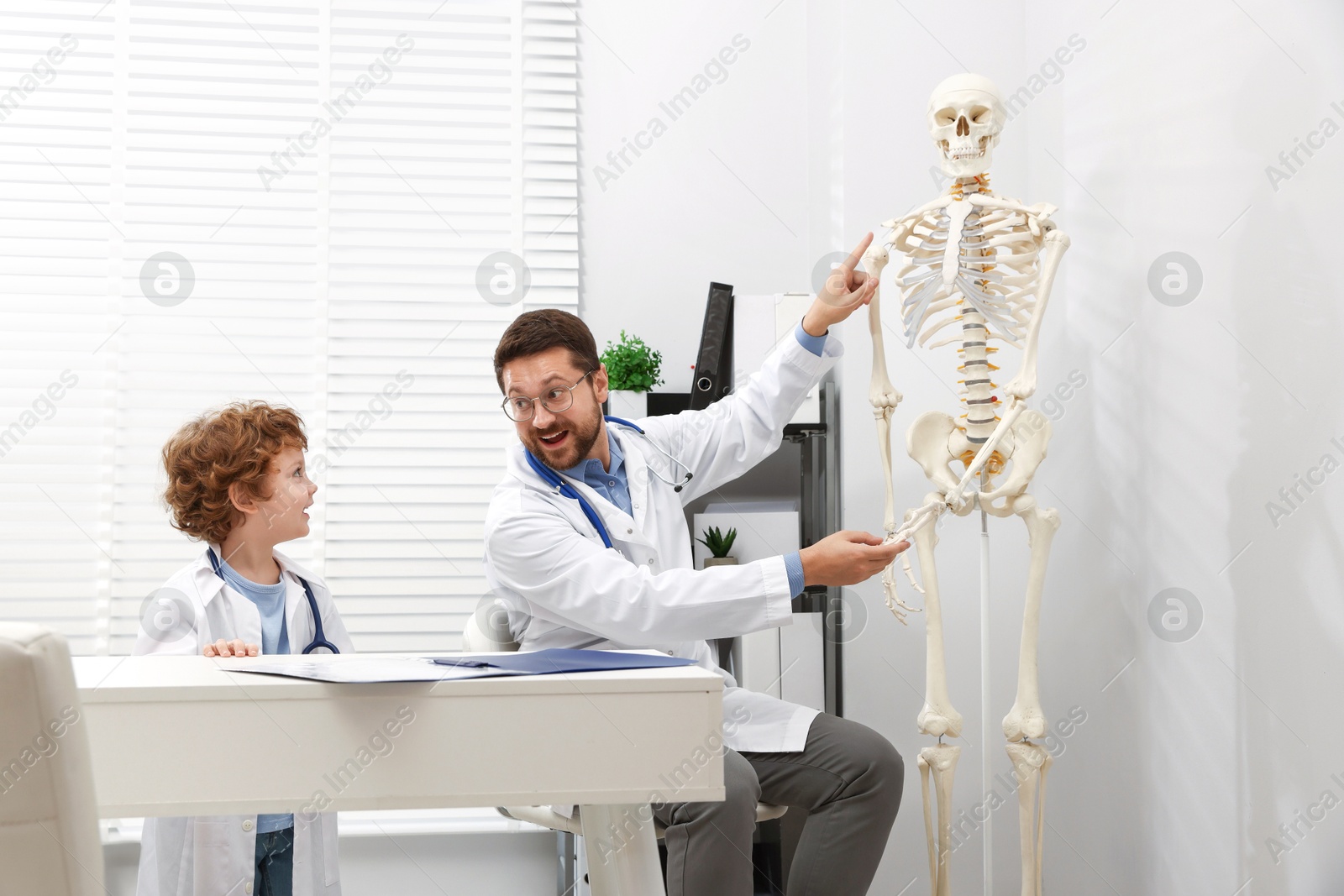Choice of profession. Father and his son exploring human skeleton model in clinic Photo of Choice of profession. Father and his son exploring human skeleton model in clinic