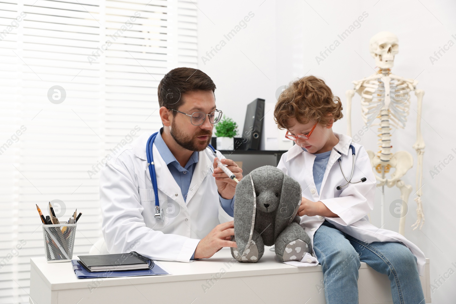 Choice of profession. Father and his son with toy bunny playing doctor in clinic Photo of Choice of profession. Father and his son with toy bunny playing doctor in clinic