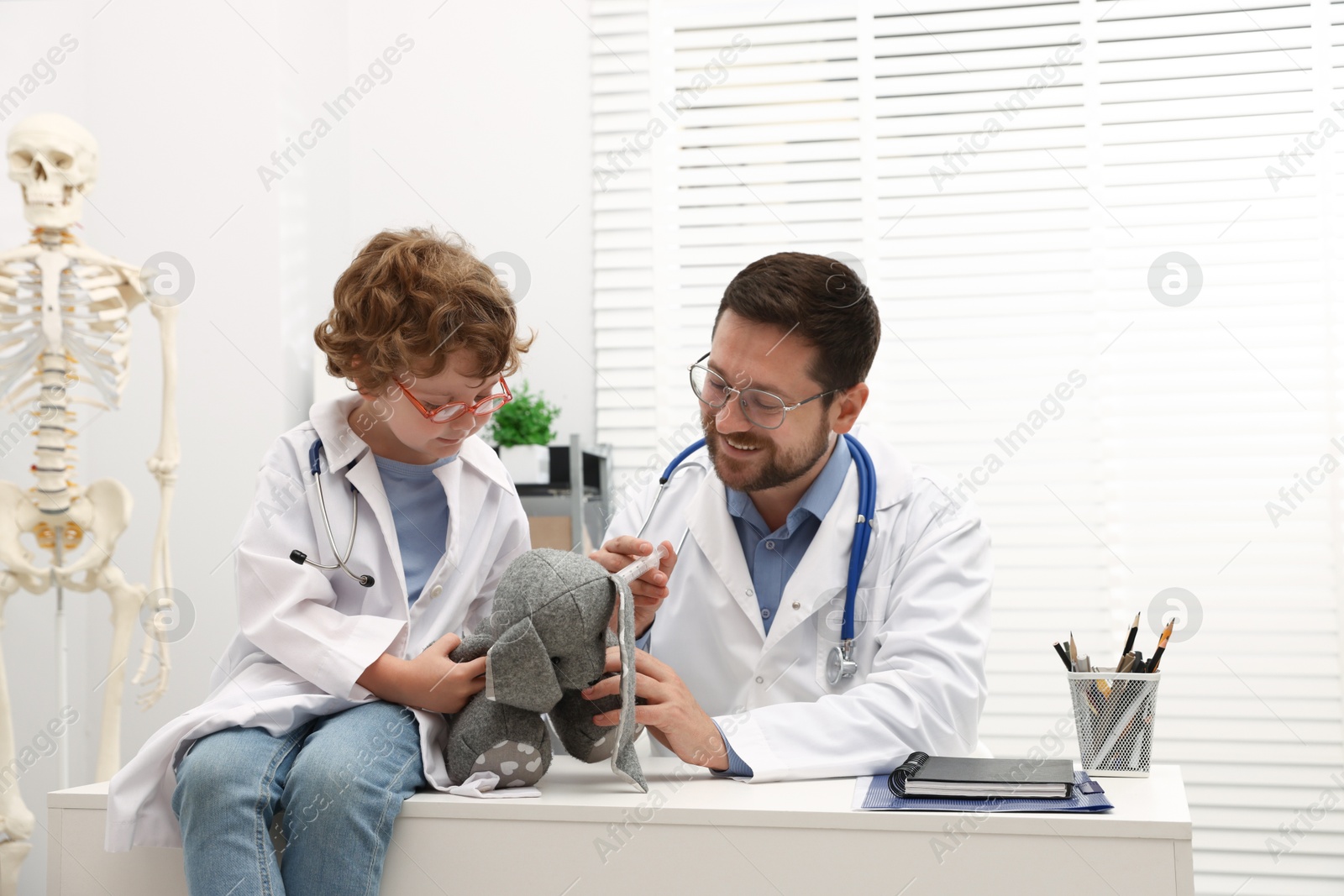 Choice of profession. Father and his son with toy bunny playing doctor in clinic Photo of Choice of profession. Father and his son with toy bunny playing doctor in clinic
