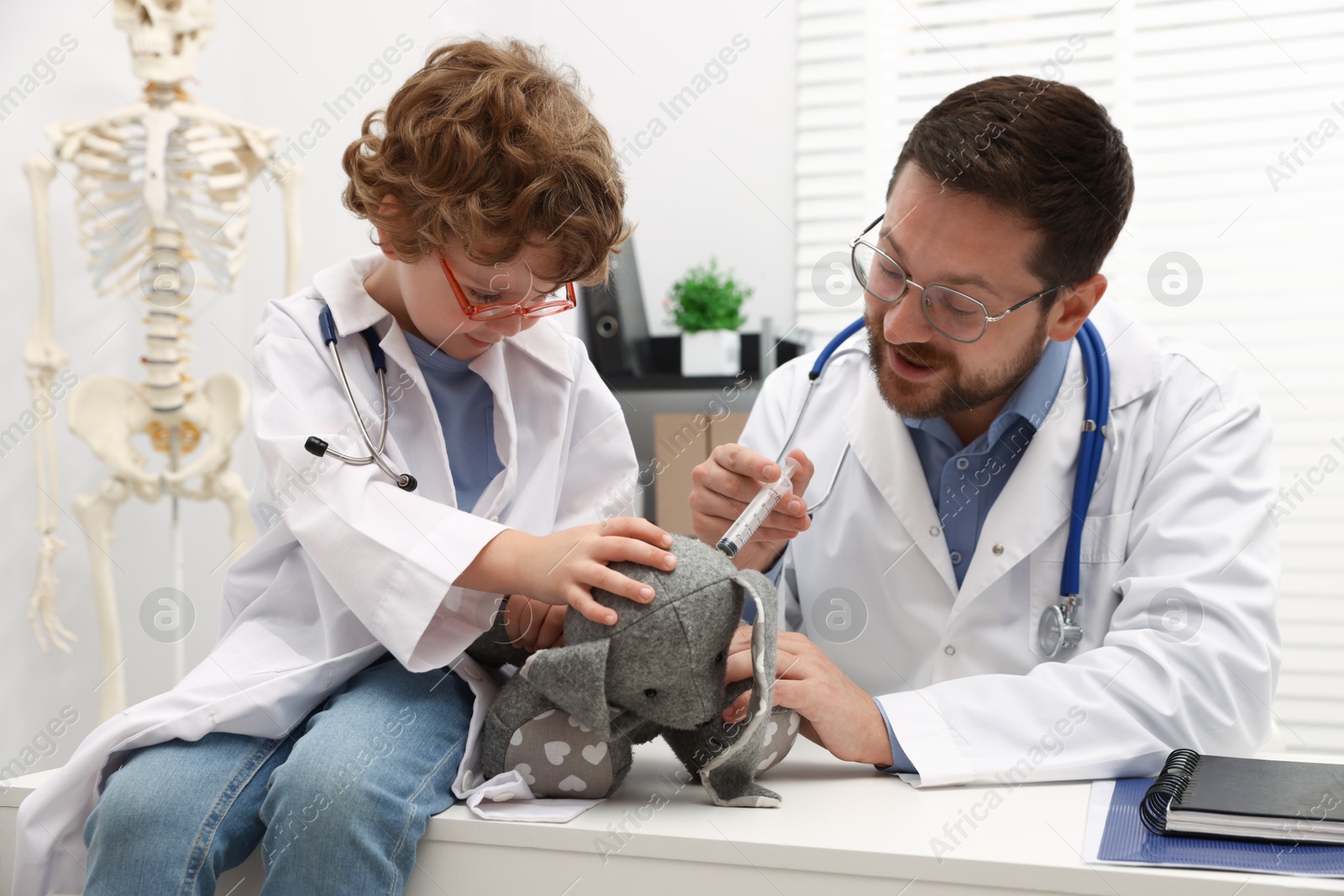 Choice of profession. Father and his son with toy bunny playing doctor in clinic Photo of Choice of profession. Father and his son with toy bunny playing doctor in clinic