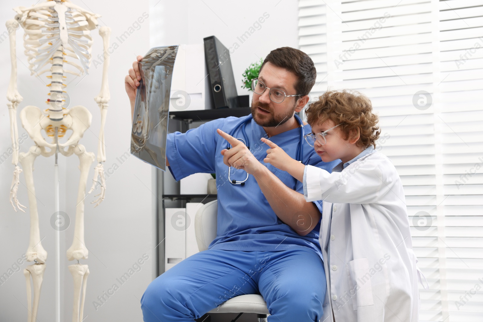 Choice of profession. Father and his son examining X-ray picture in clinic Photo of Choice of profession. Father and his son examining X-ray picture in clinic