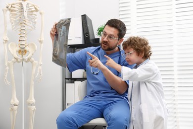 Photo of Choice of profession. Father and his son examining X-ray picture in clinic