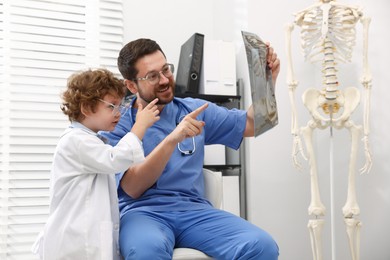 Photo of Choice of profession. Father and his son examining X-ray picture in clinic