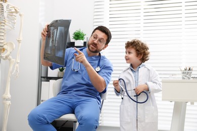 Photo of Choice of profession. Father and his son examining X-ray picture in clinic