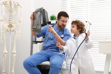 Photo of Choice of profession. Father and his son examining X-ray picture in clinic