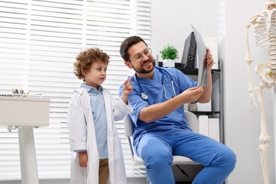 Photo of Choice of profession. Father and his son examining X-ray picture in clinic