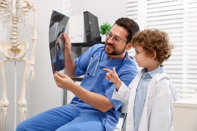 Photo of Choice of profession. Father and his son examining X-ray picture in clinic