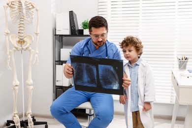 Photo of Choice of profession. Father and his son examining X-ray picture in clinic