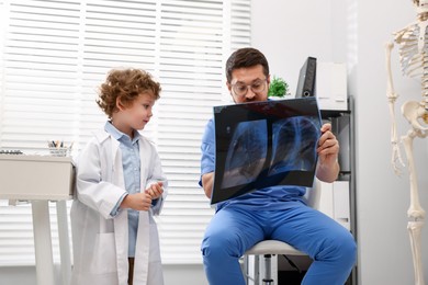 Photo of Choice of profession. Father and his son examining X-ray picture in clinic