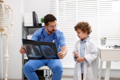 Photo of Choice of profession. Father and his son examining X-ray picture in clinic
