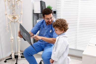 Photo of Choice of profession. Father and his son examining X-ray picture in clinic