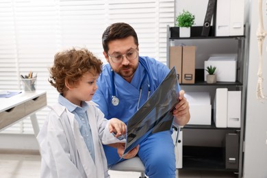 Photo of Choice of profession. Father and his son examining X-ray picture in clinic
