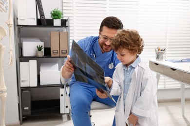 Photo of Choice of profession. Father and his son examining X-ray picture in clinic