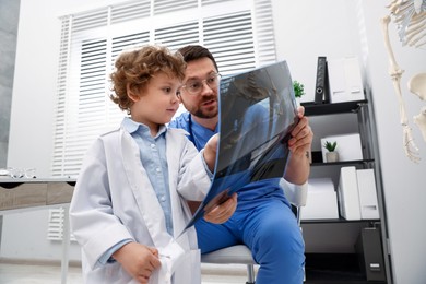 Photo of Choice of profession. Father and his son examining X-ray picture in clinic