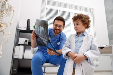 Photo of Choice of profession. Father and his son examining X-ray picture in clinic