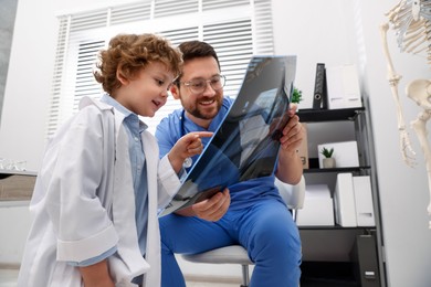 Photo of Choice of profession. Father and his son examining X-ray picture in clinic