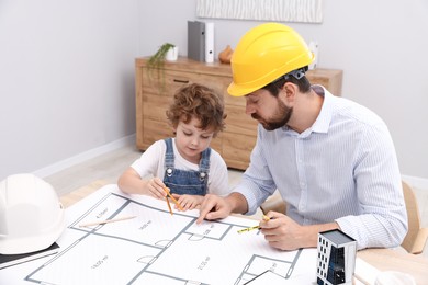 Photo of Choice of profession. Father and his son with dividers exploring engineering drawings at table indoors