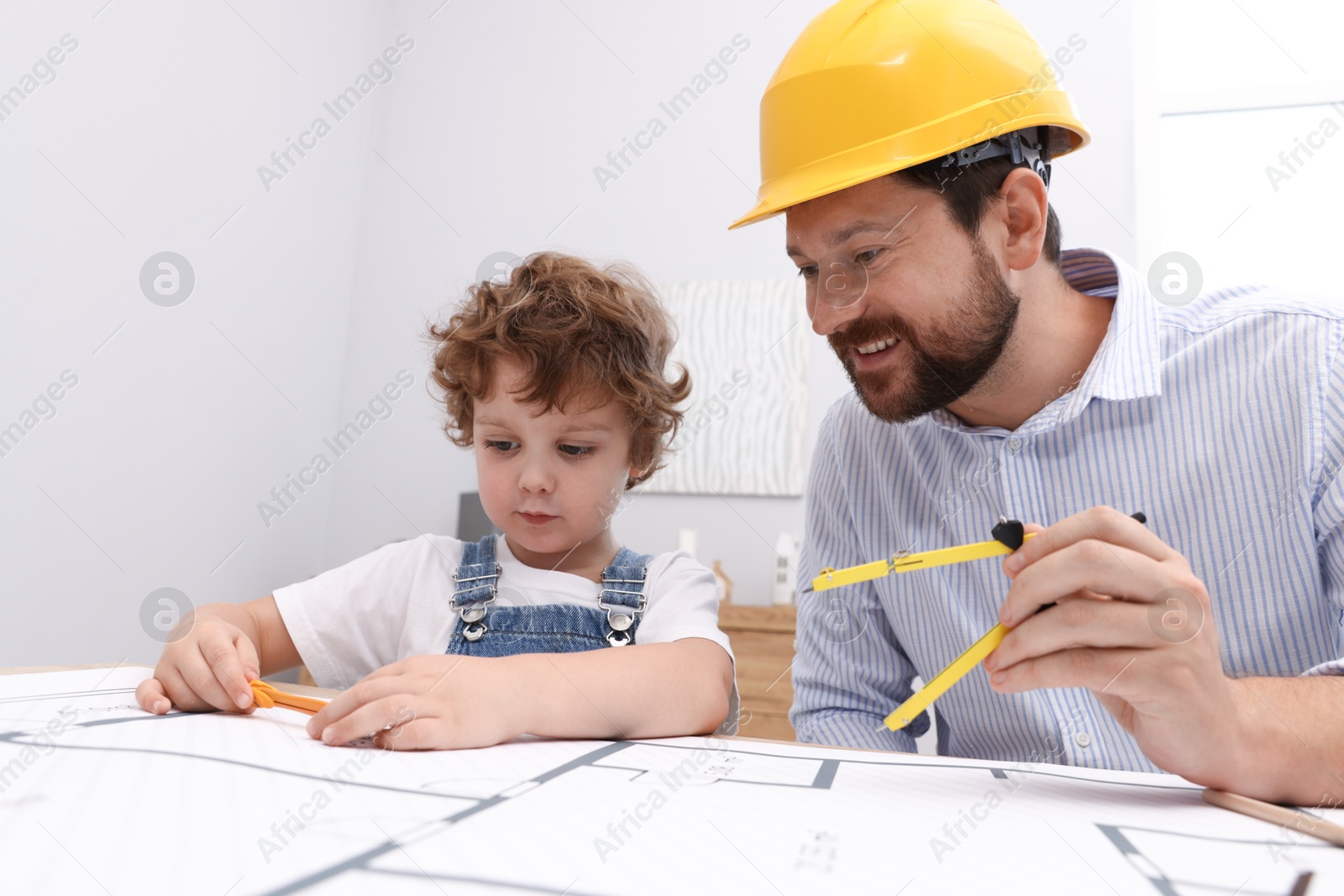 Choice of profession. Father and his son with dividers exploring engineering drawings at table indoors Photo of Choice of profession. Father and his son with dividers exploring engineering drawings at table indoors