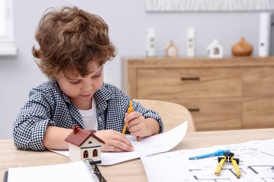 Photo of Choice of profession. Little kid with divider and engineering drawing at table indoors