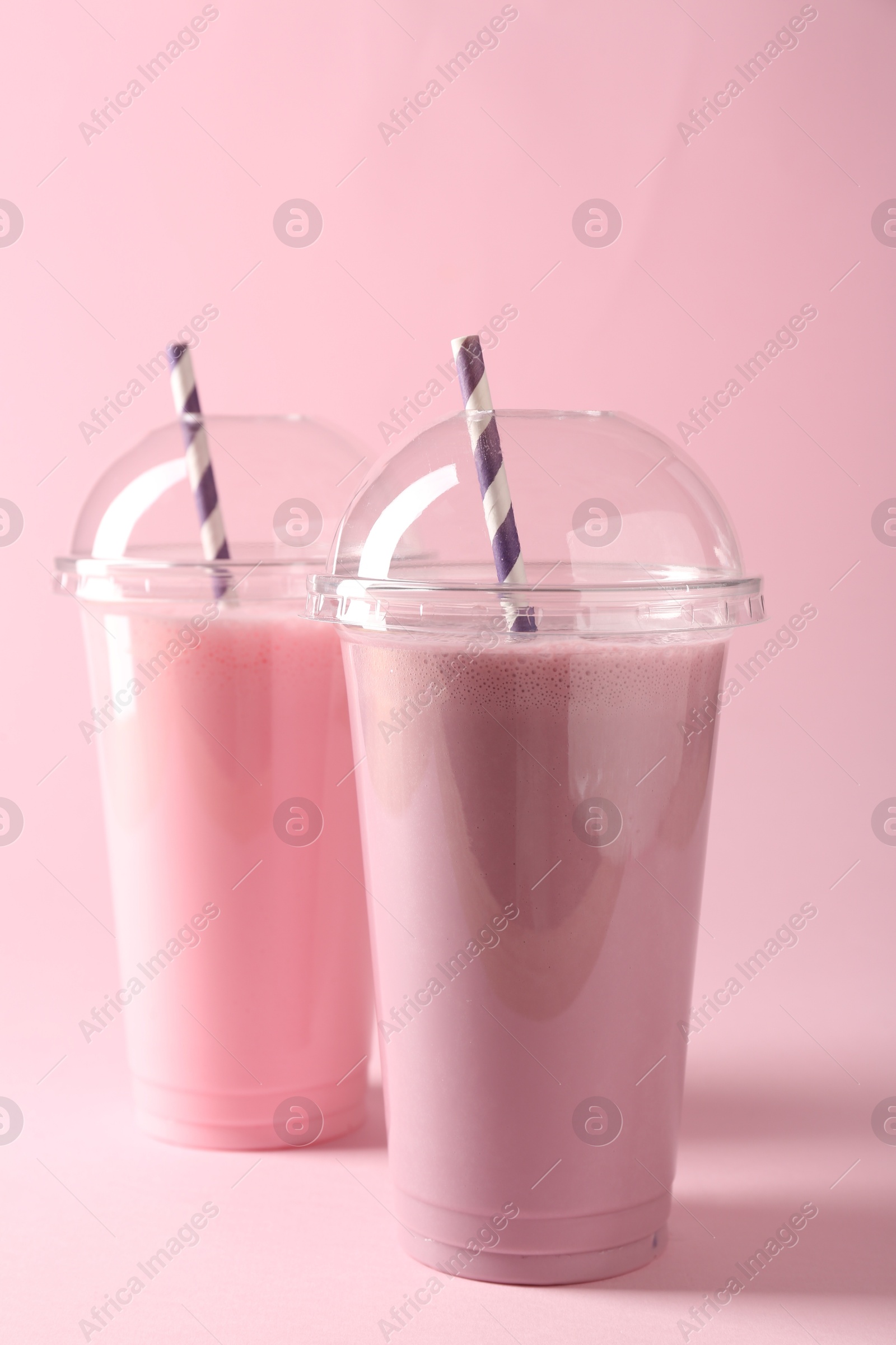 Tasty milkshakes in plastic cups on pink background Photo of Tasty milkshakes in plastic cups on pink background