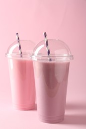 Photo of Tasty milkshakes in plastic cups on pink background