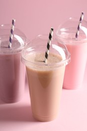 Photo of Tasty milkshakes in plastic cups on pink background